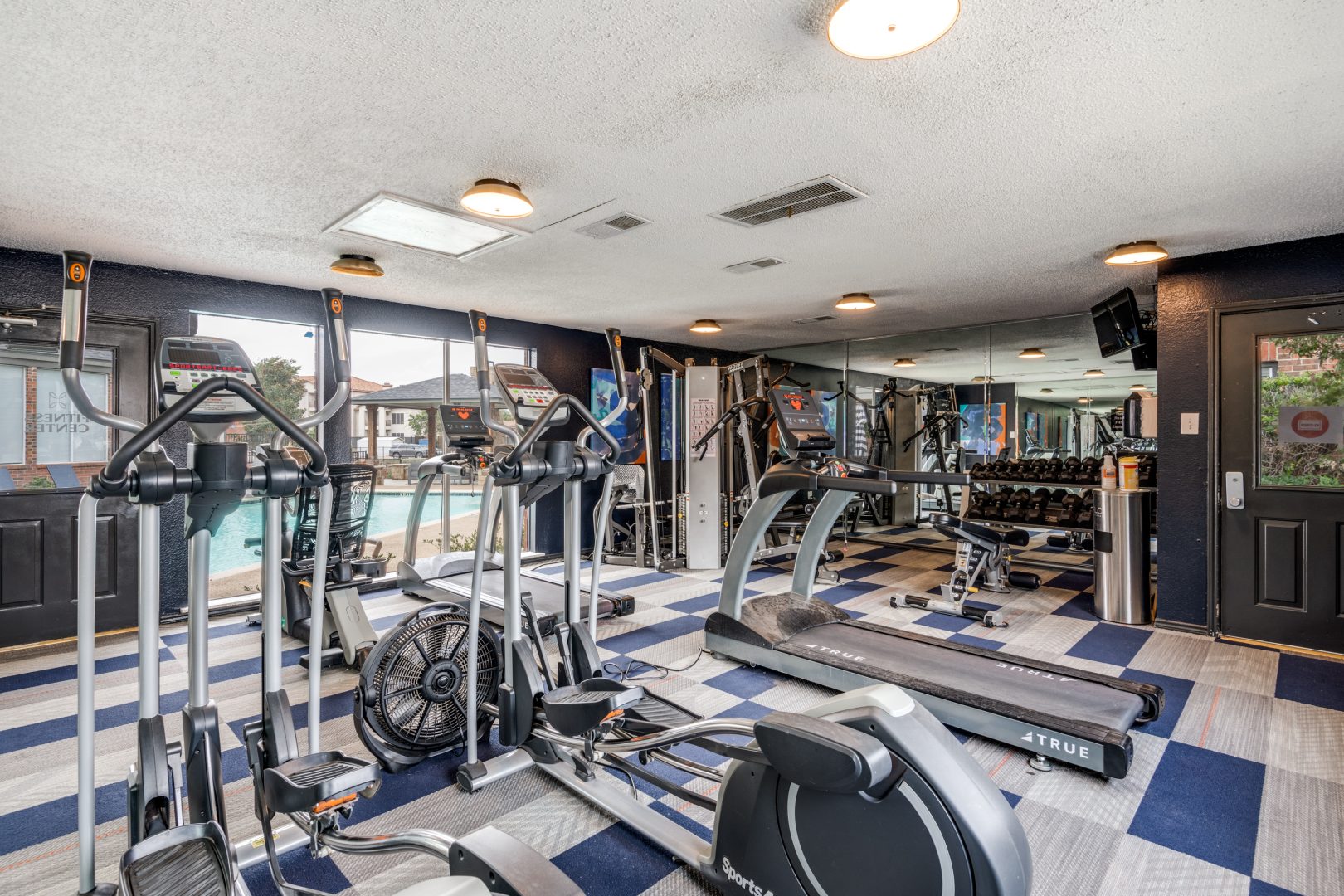 a gym room with treadmills and exercise equipment at The  Hathaway at Willow Bend