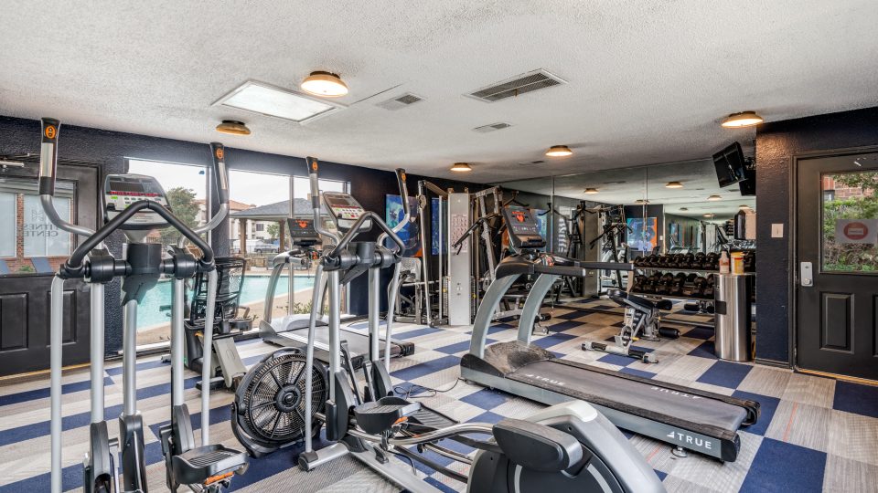 a gym room with treadmills and exercise equipment at The  Hathaway at Willow Bend
